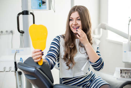 woman looking at her new smile at the dentist